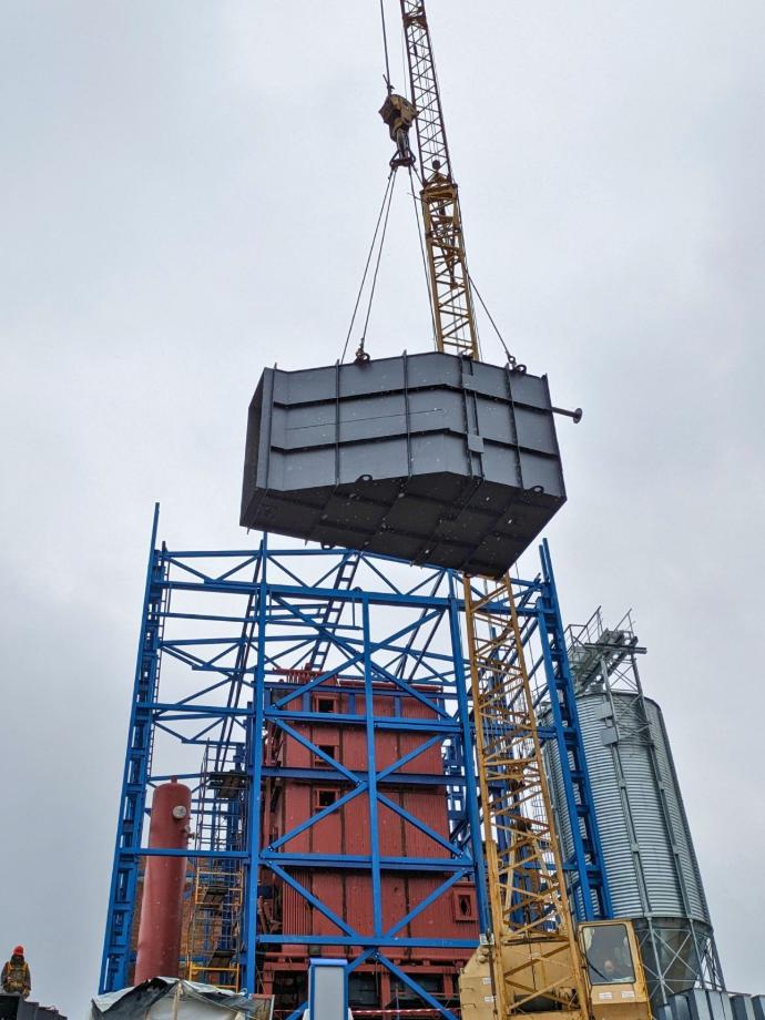 Монтаж витратного бункера палива краном на майданчику котельні, що будується